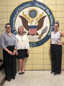 Teachers from Jersey City Academy in front of their school logo.